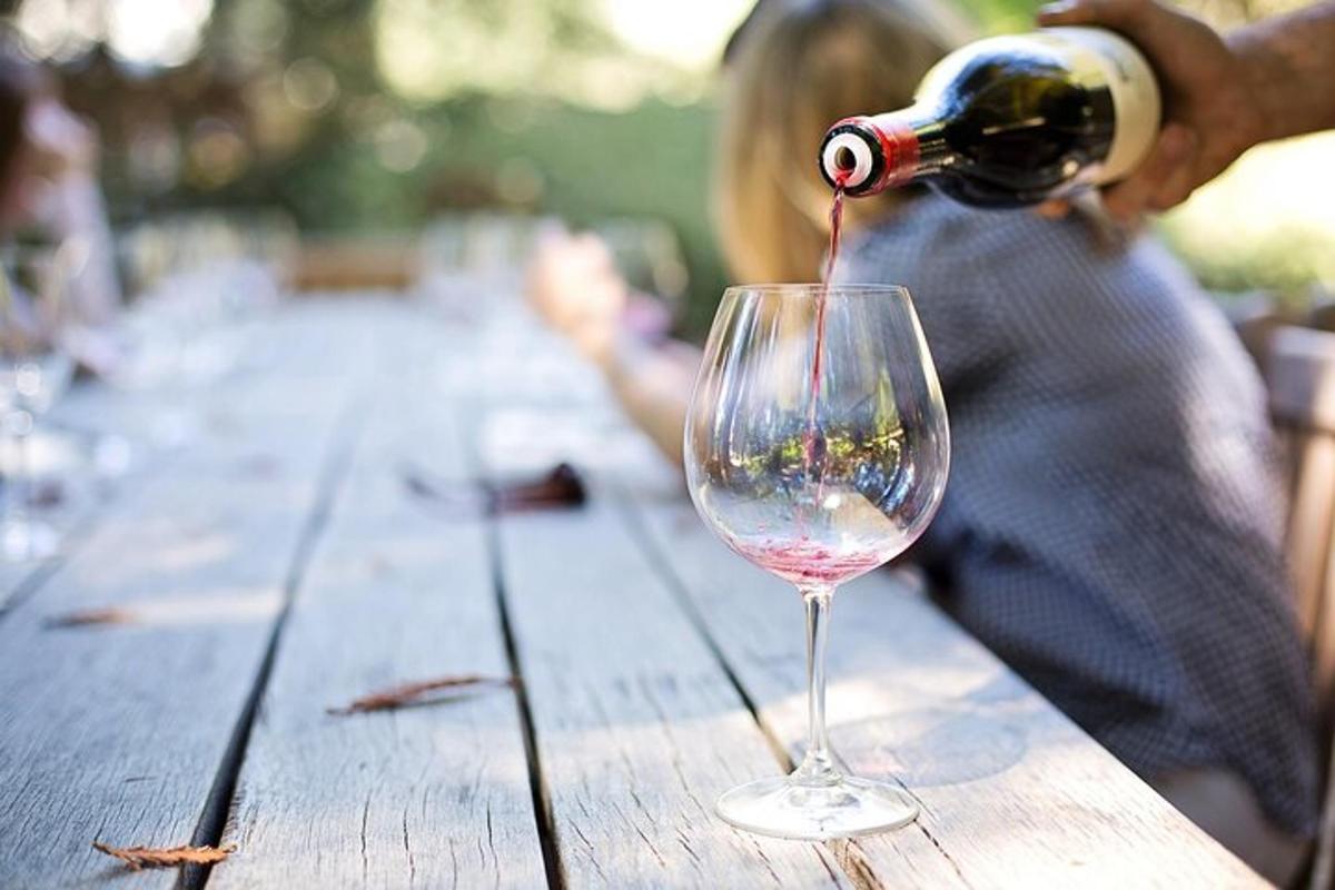 oseba, ki na leseni mizi nalije vino v vinski kozarec