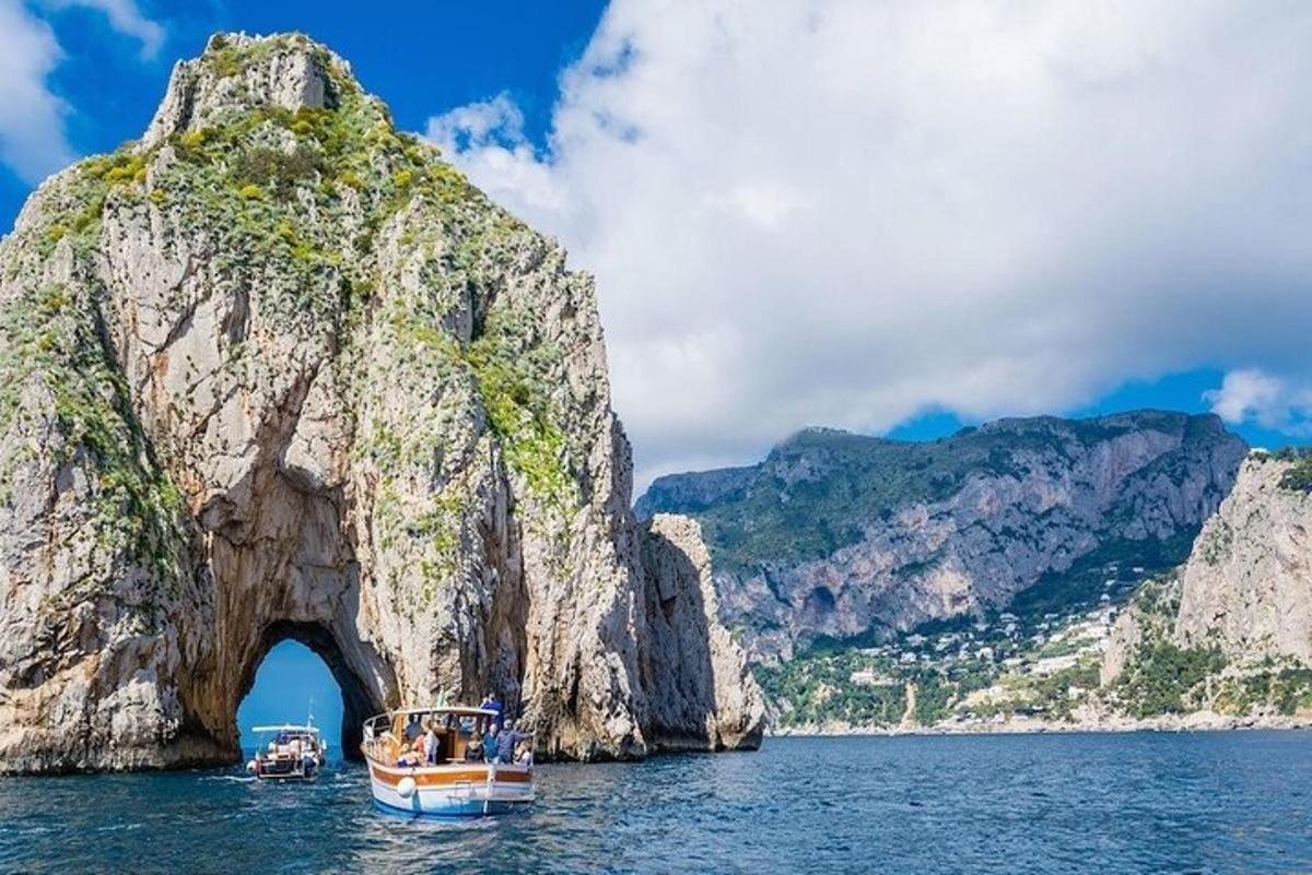a boat in the water next to a rock formation