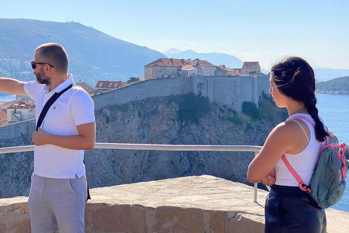 Ένας άντρας και μια γυναίκα στέκονται σε ένα περβάζι κοιτάζοντας ένα κάστρο