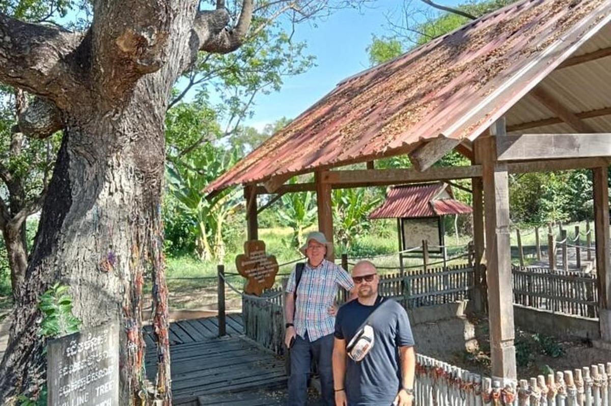 два мушкарца стоје на дрвеној стази испред дрвета