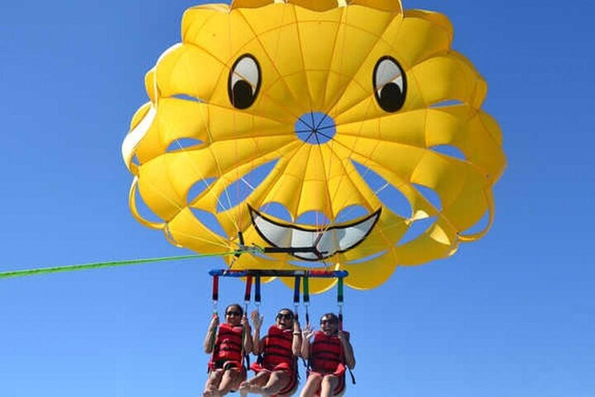 three people on a yellow kite with a face on it