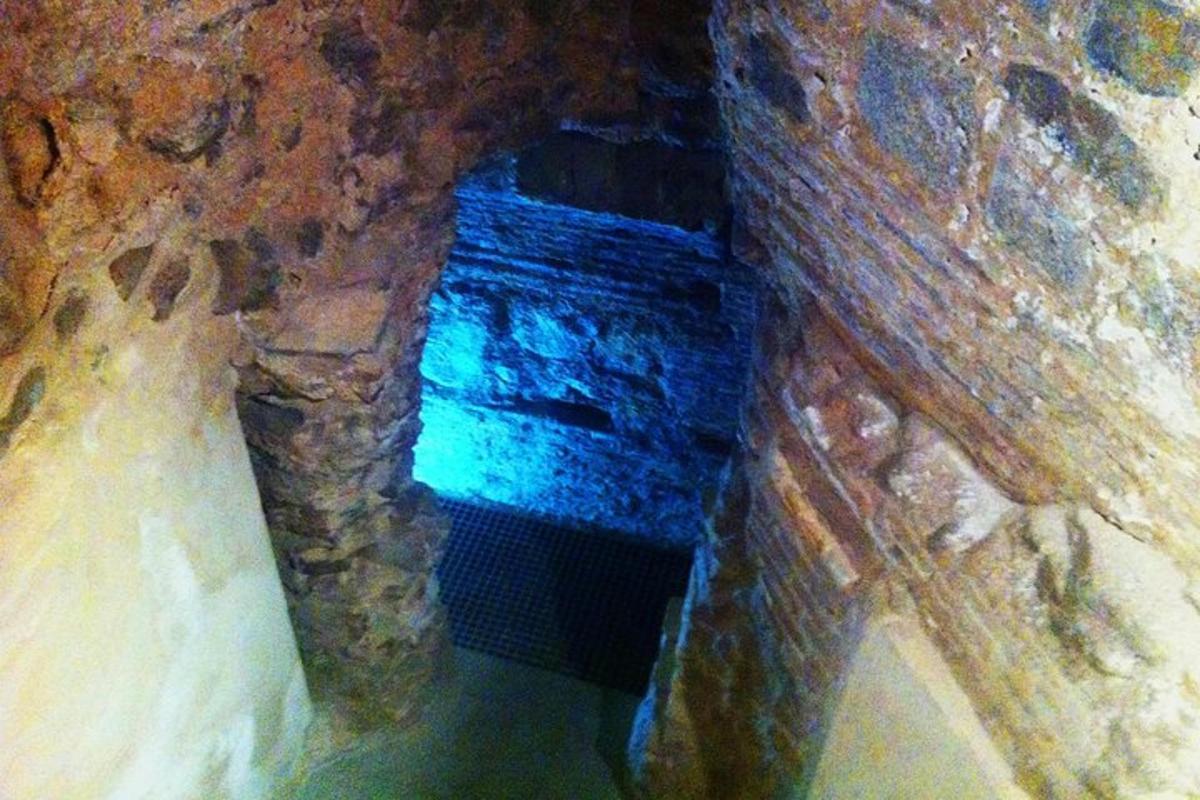 a stone tunnel with a blue light in a cave