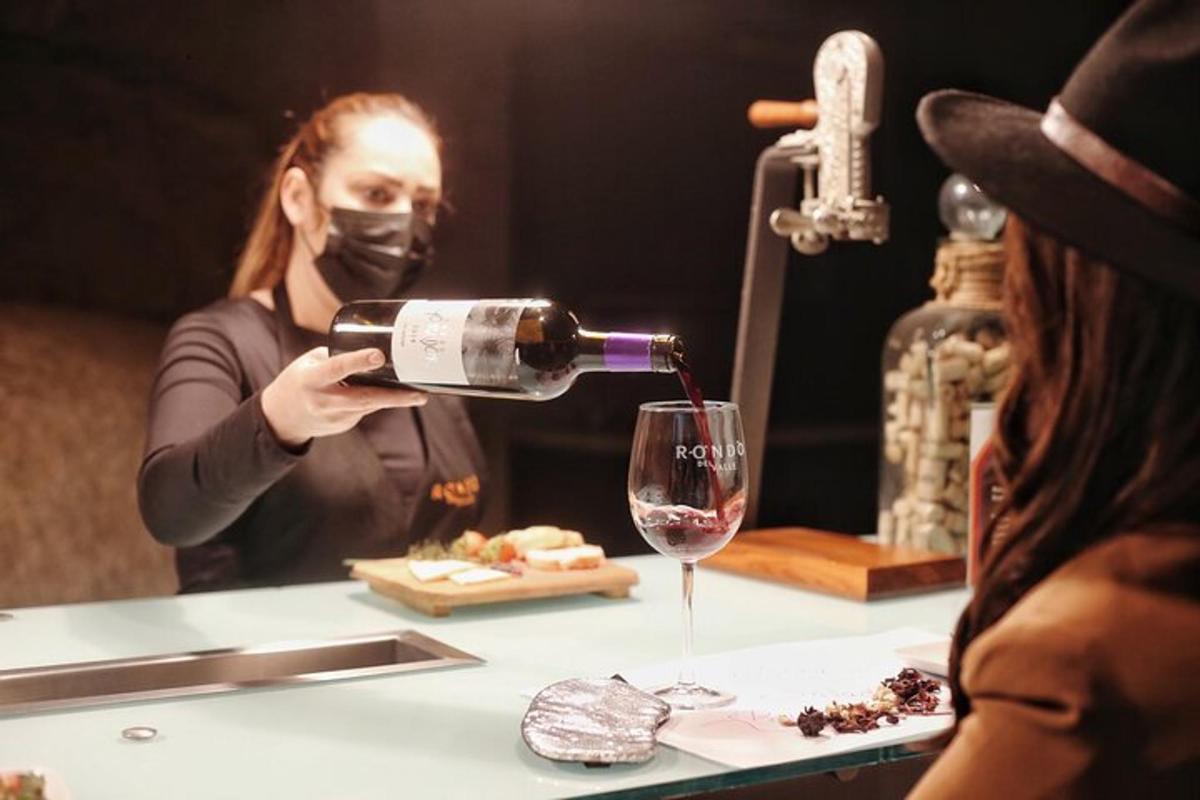 o femeie cu mască toarnă vin într-un pahar