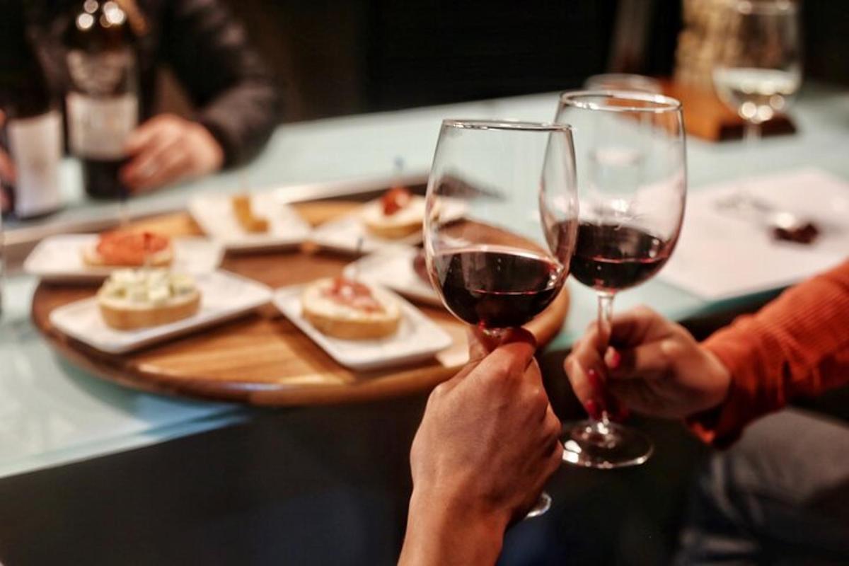 Dos personas sostienen copas de vino tinto.