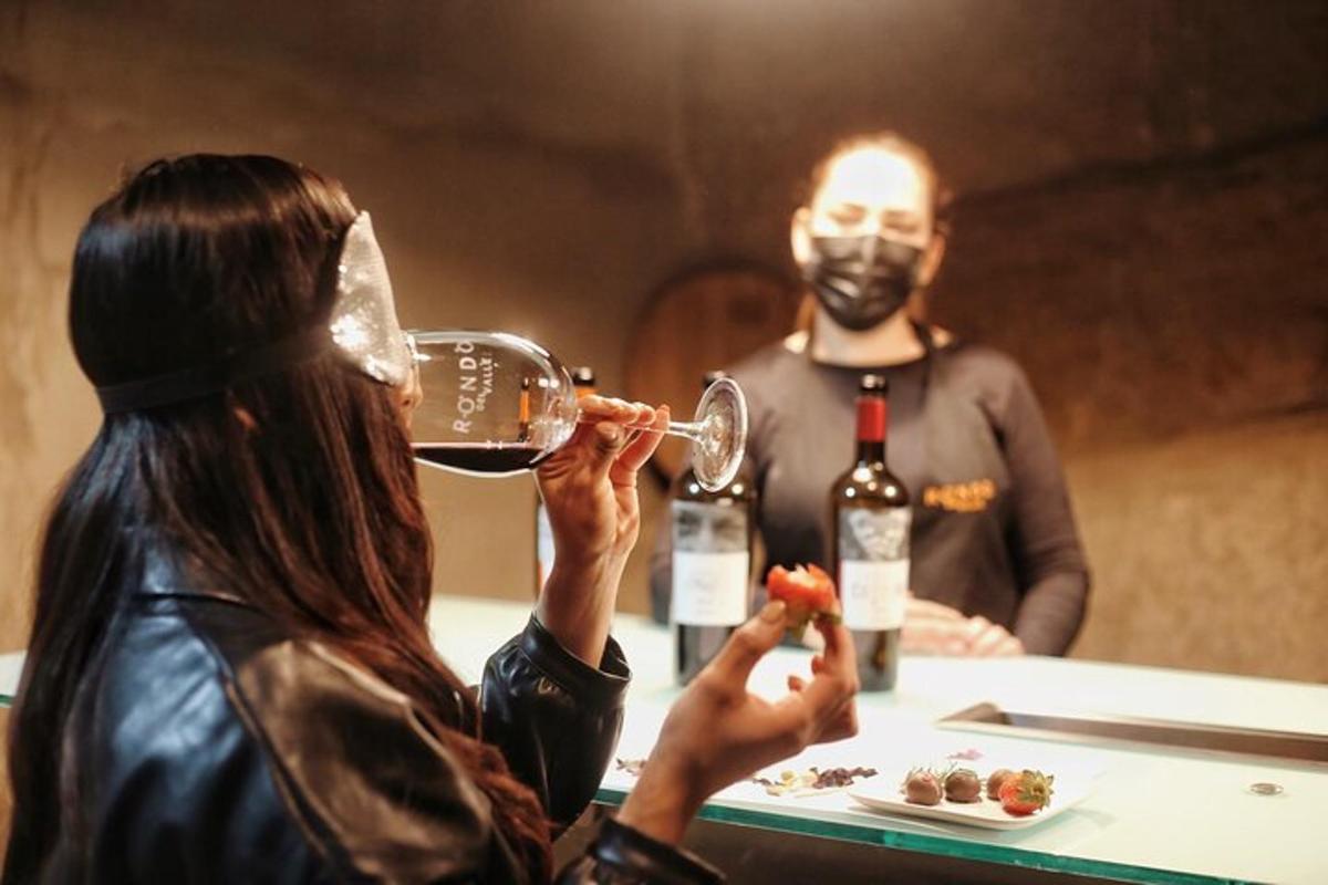 o femeie care bea un pahar de vin cu un bărbat care poartă o mască