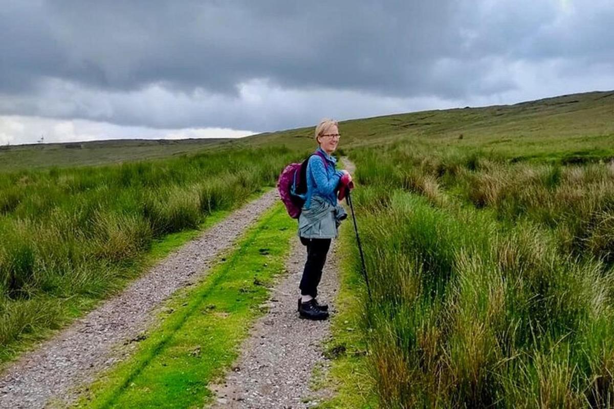 a woman walking down a dirt road with a backpack