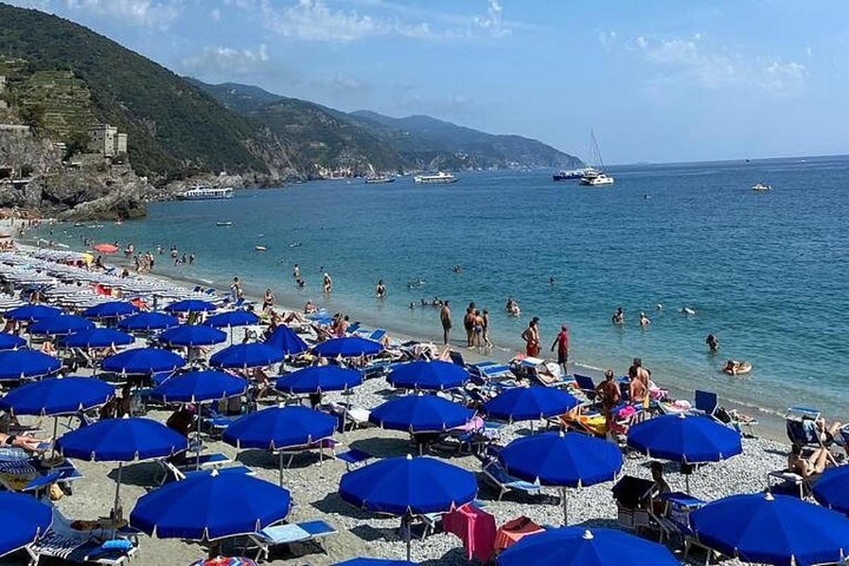 una platja amb para-sols blaus i gent a l'aigua