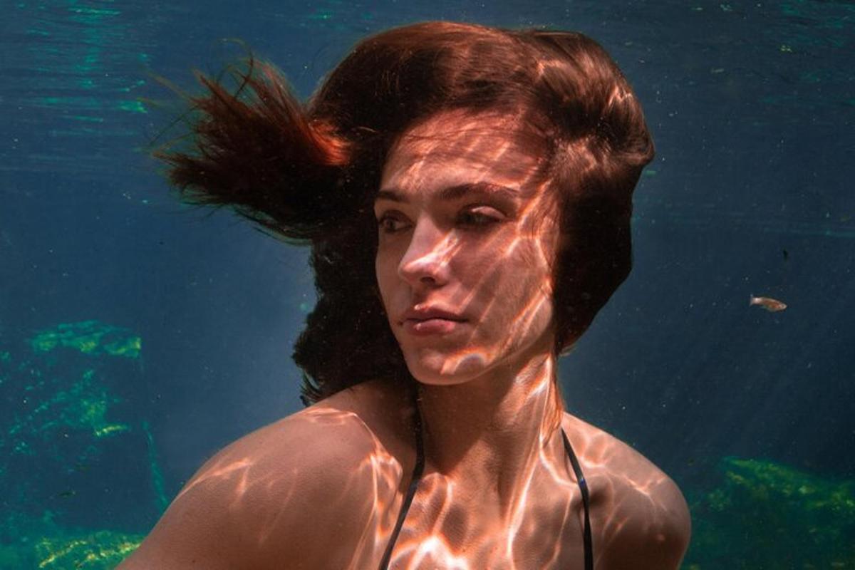 髪を浮かべて水中を泳ぐ女性