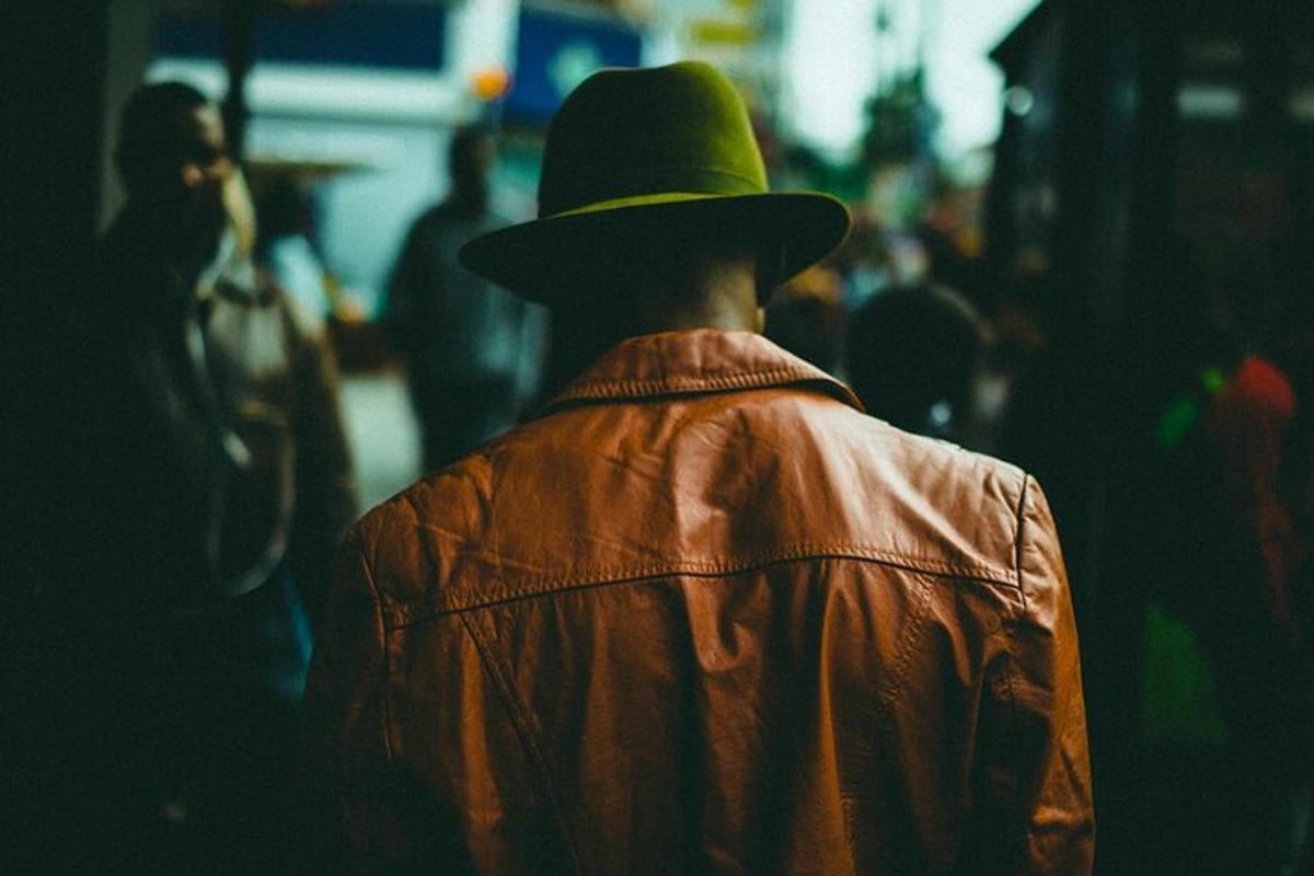 a man wearing a brown jacket and a green hat