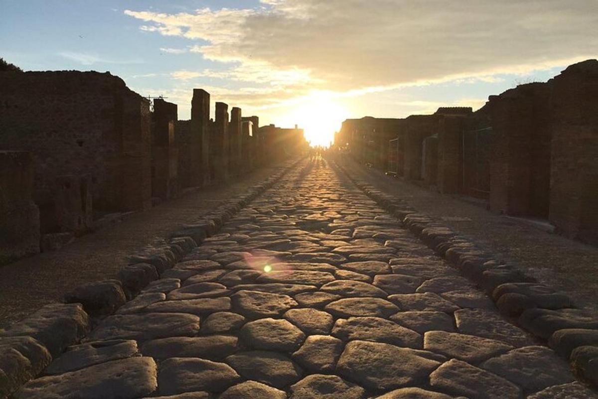 a stone road with the sun setting in the distance
