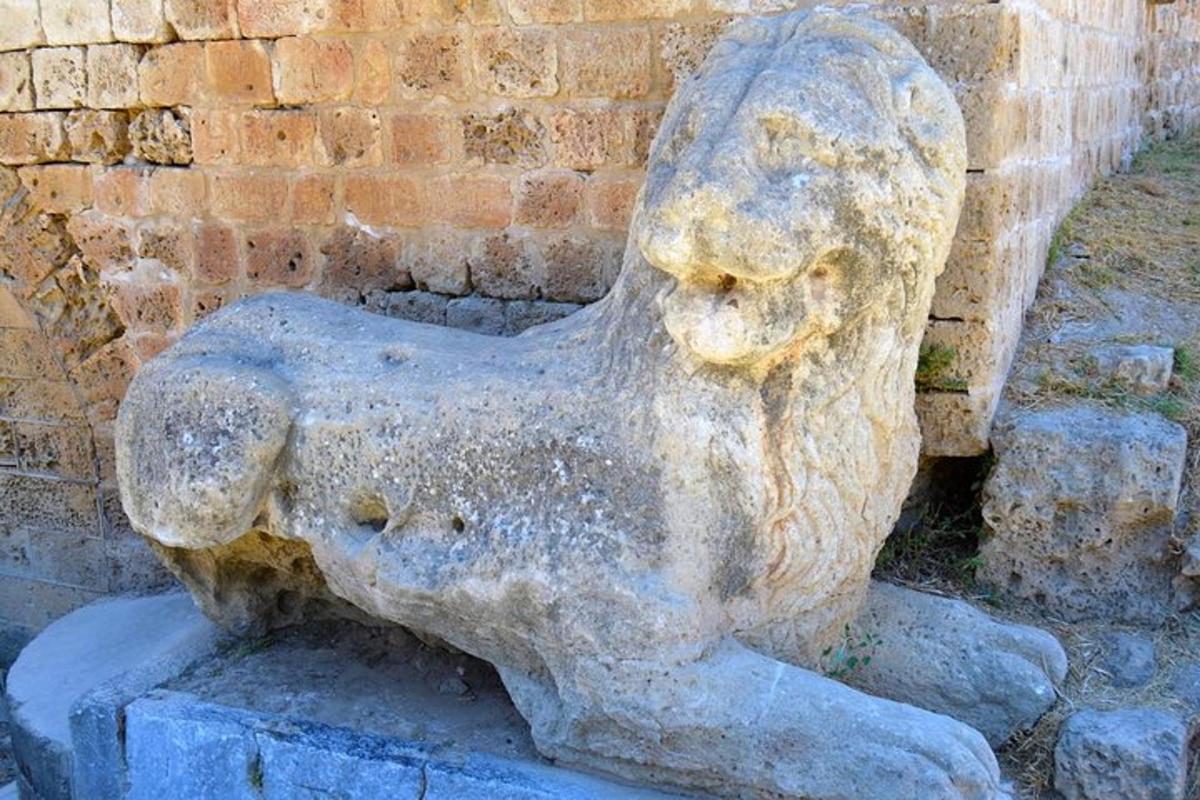 una statua di leone di pietra seduta accanto a un muro di mattoni
