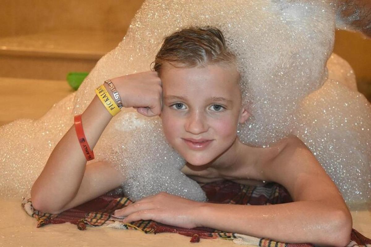 seorang budak lelaki dalam tab mandi yang dilitupi buih