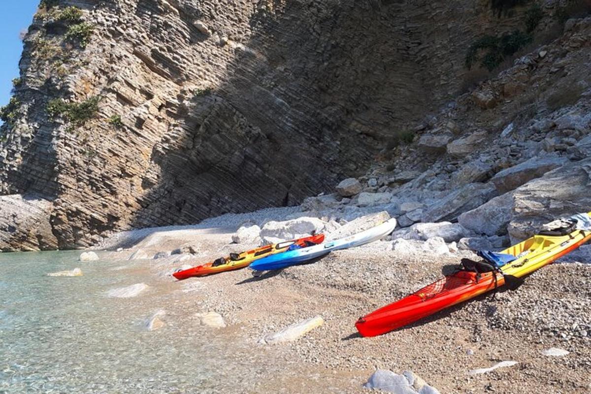 três caiaques em uma praia rochosa perto da água
