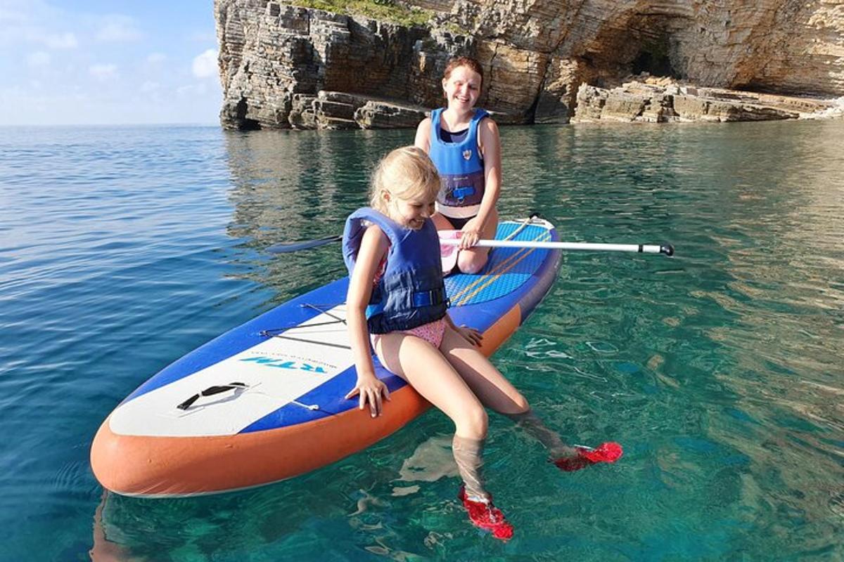 o femeie și o fată stând pe o placă de paddle în apă