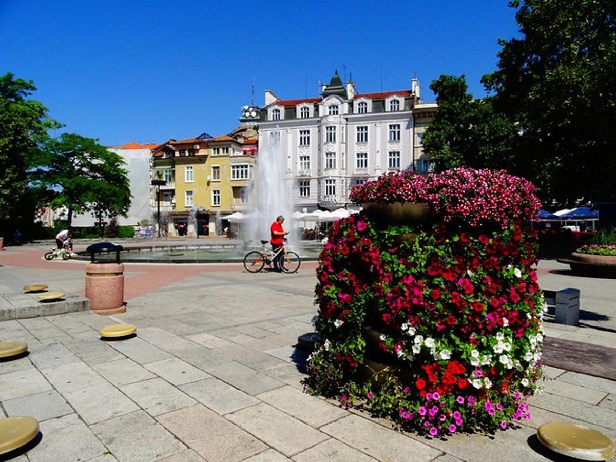 a person riding a bike next to a fountain with flowers