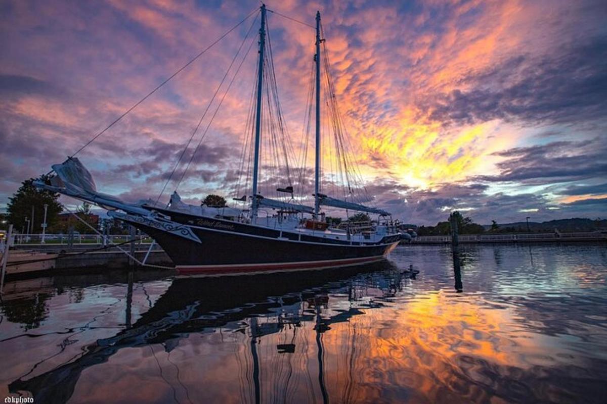 a boat sitting in the water with a sunset