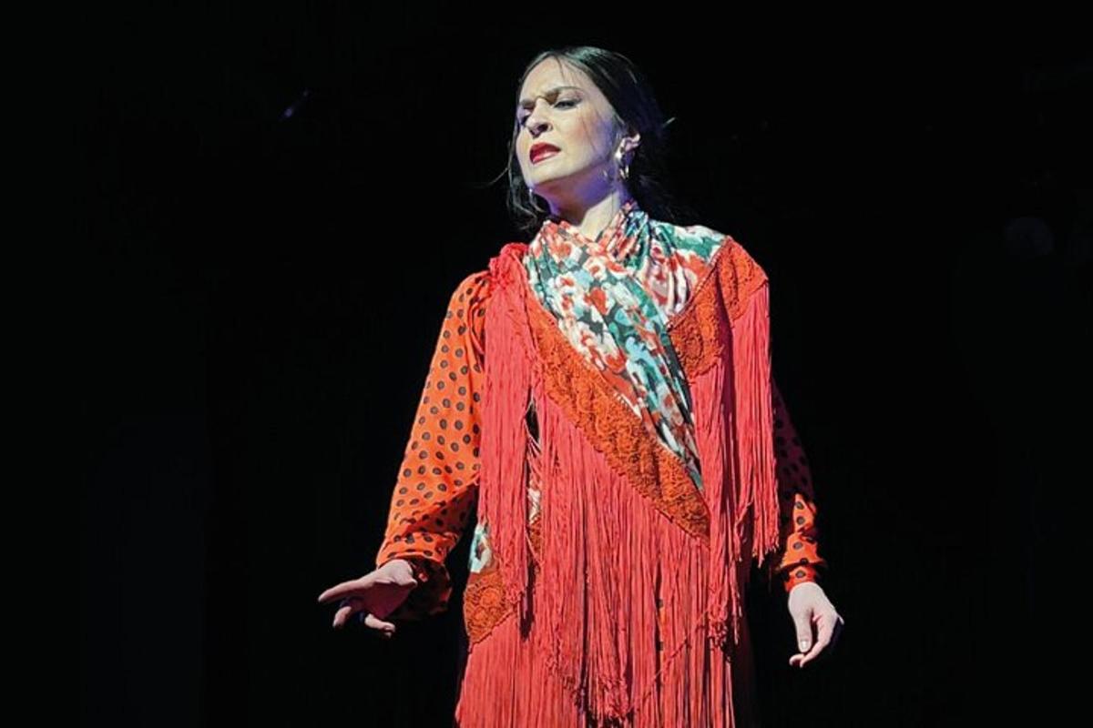 uma mulher em pé no palco usando um vestido vermelho