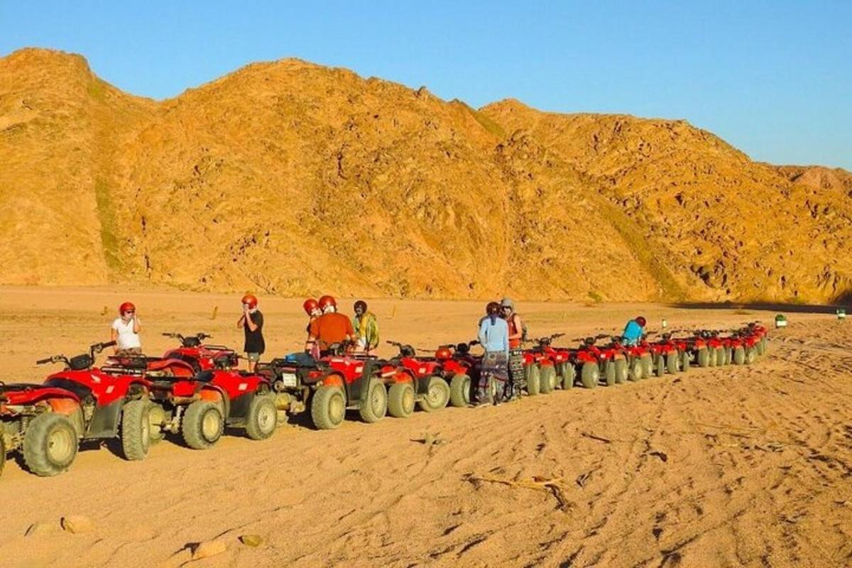 a large group of people standing around atvs in the desert