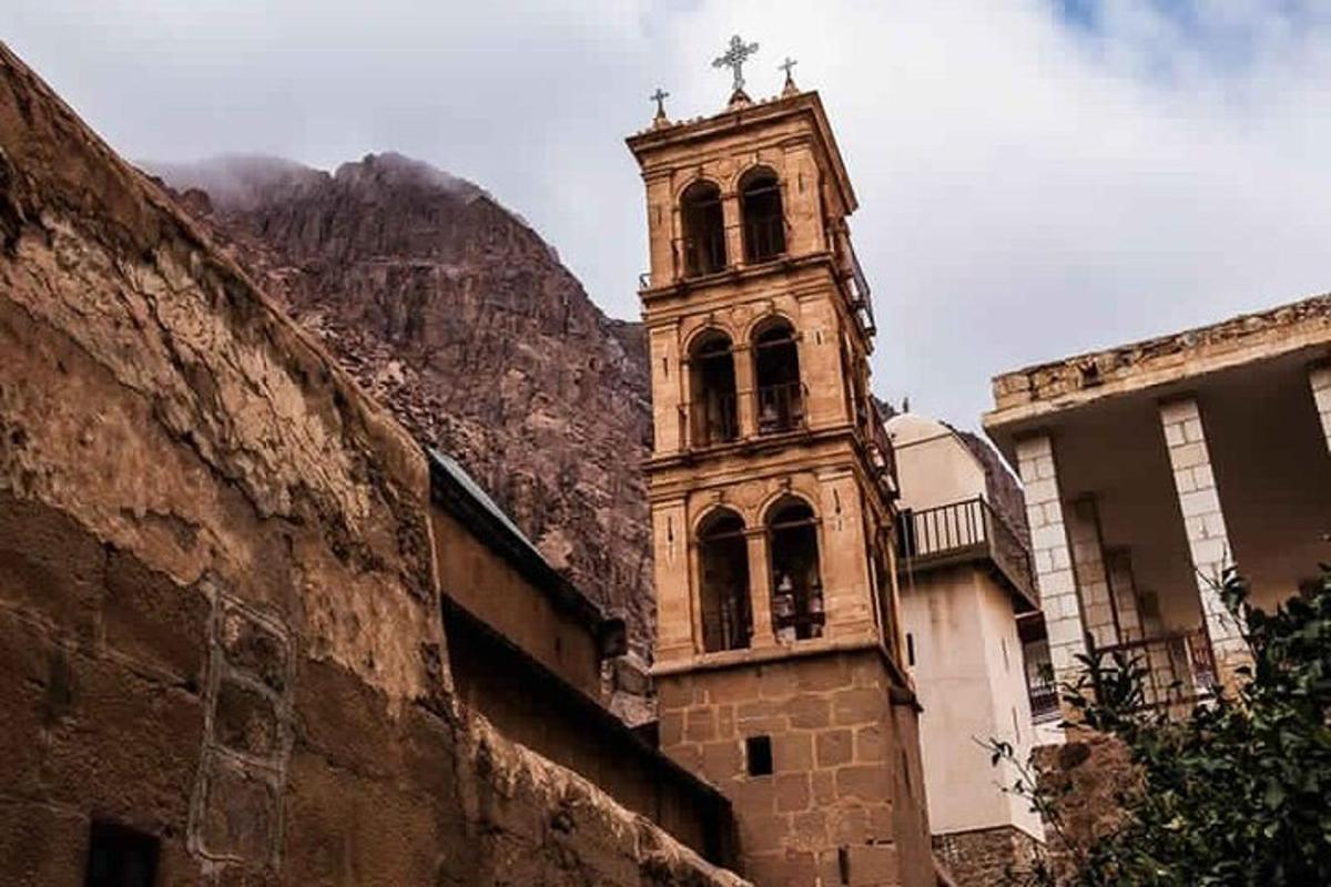 a building with a clock tower in front of a mountain