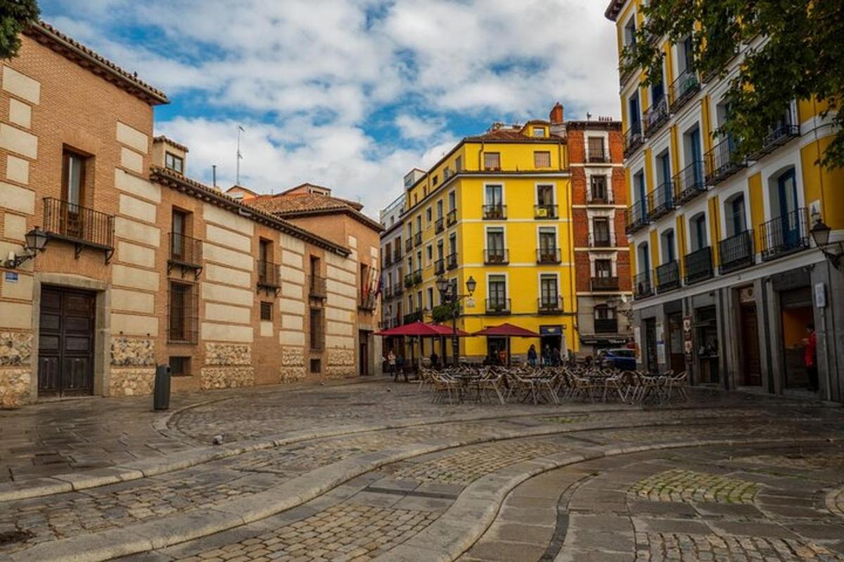 a cobblestone street with chairs and buildings in a city