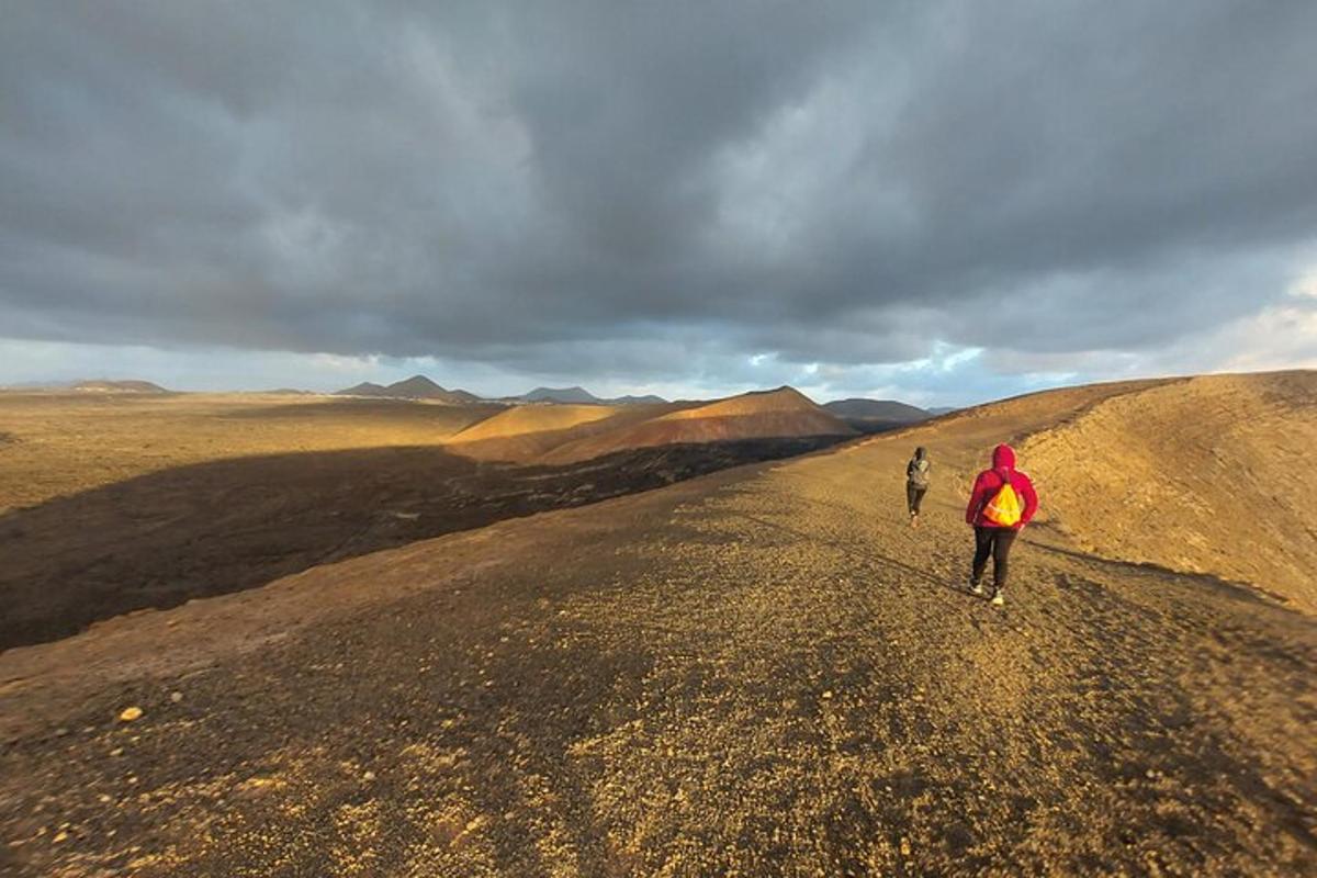 two people walking down a dirt road on a hill