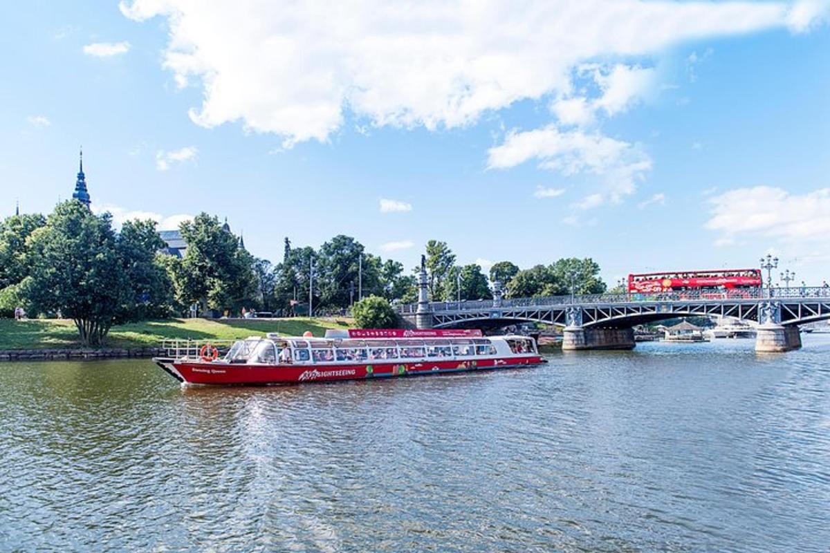 a red boat on a river with a bridge