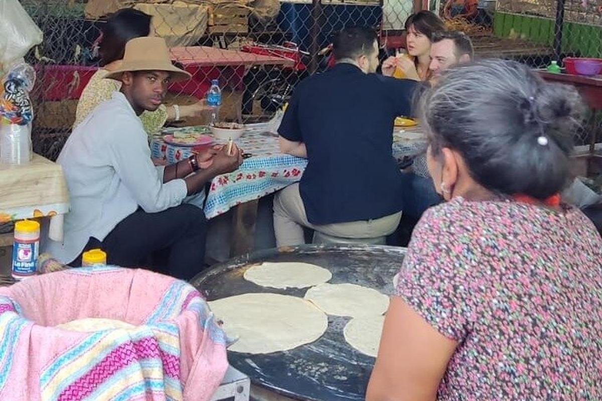 a group of people sitting around a table making pizza