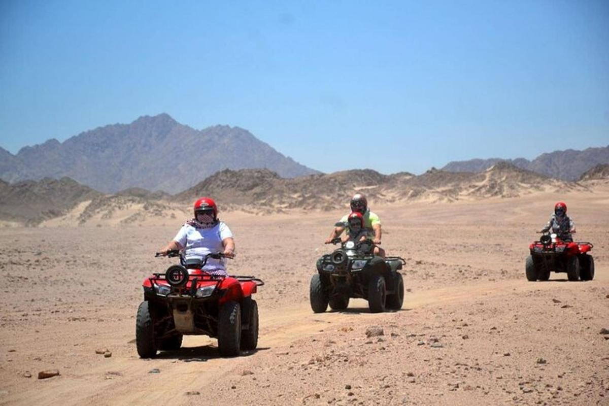 Tres personas viajan en vehículos todo terreno en el desierto.
