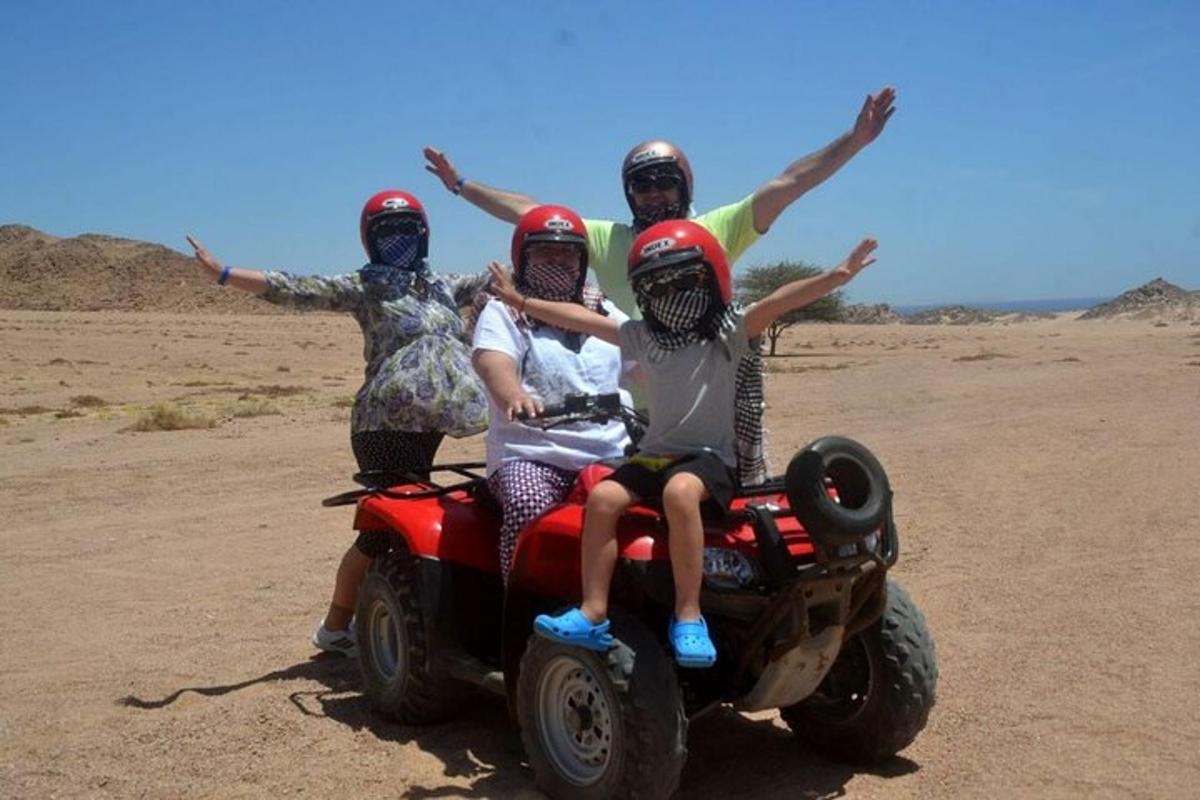 Tres personas en un vehículo de cuatro ruedas en el desierto