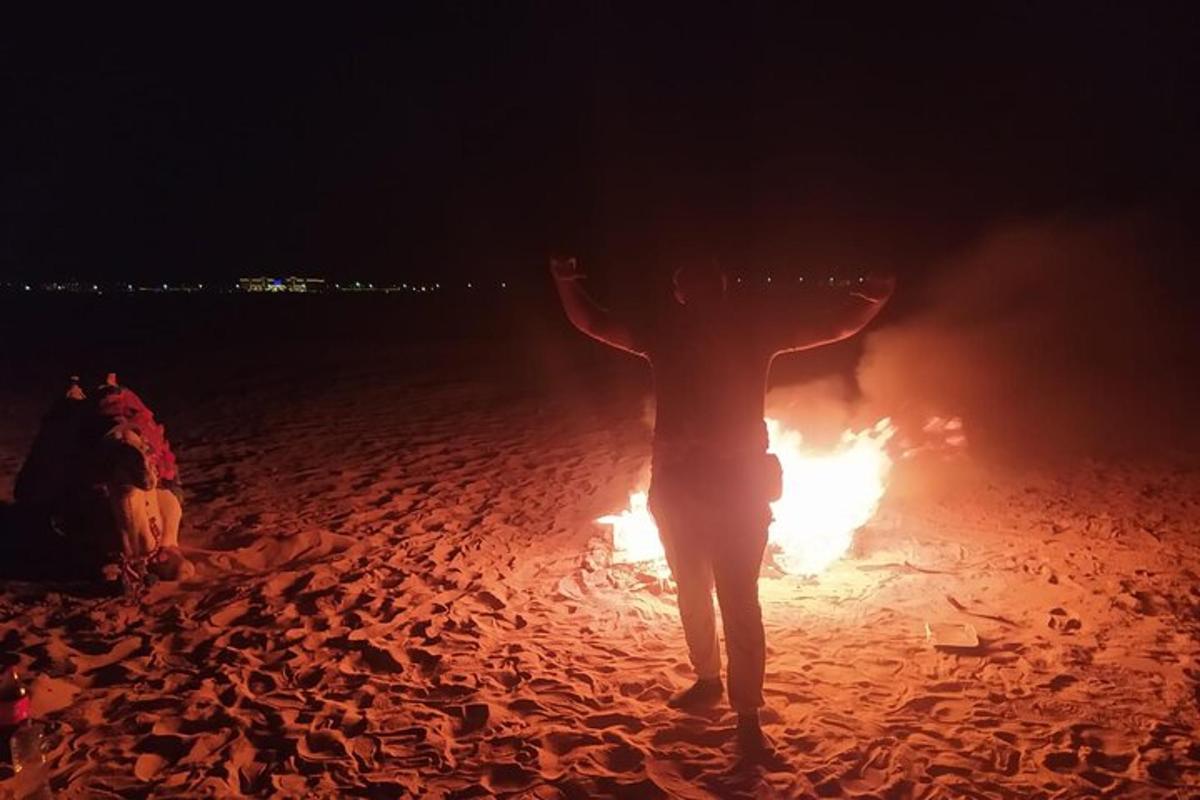 eine Person, die mit einem Feuer an einem Strand steht