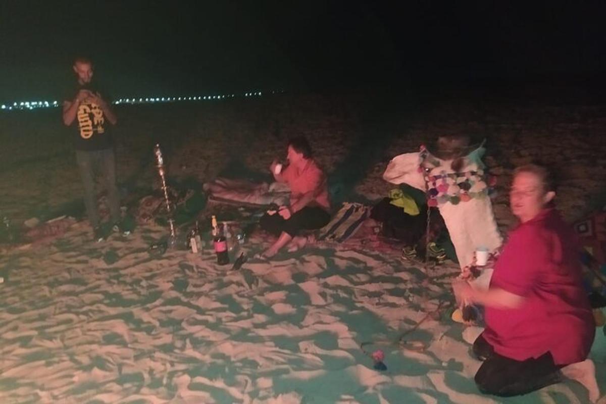 eine Gruppe von Menschen sitzt nachts am Strand