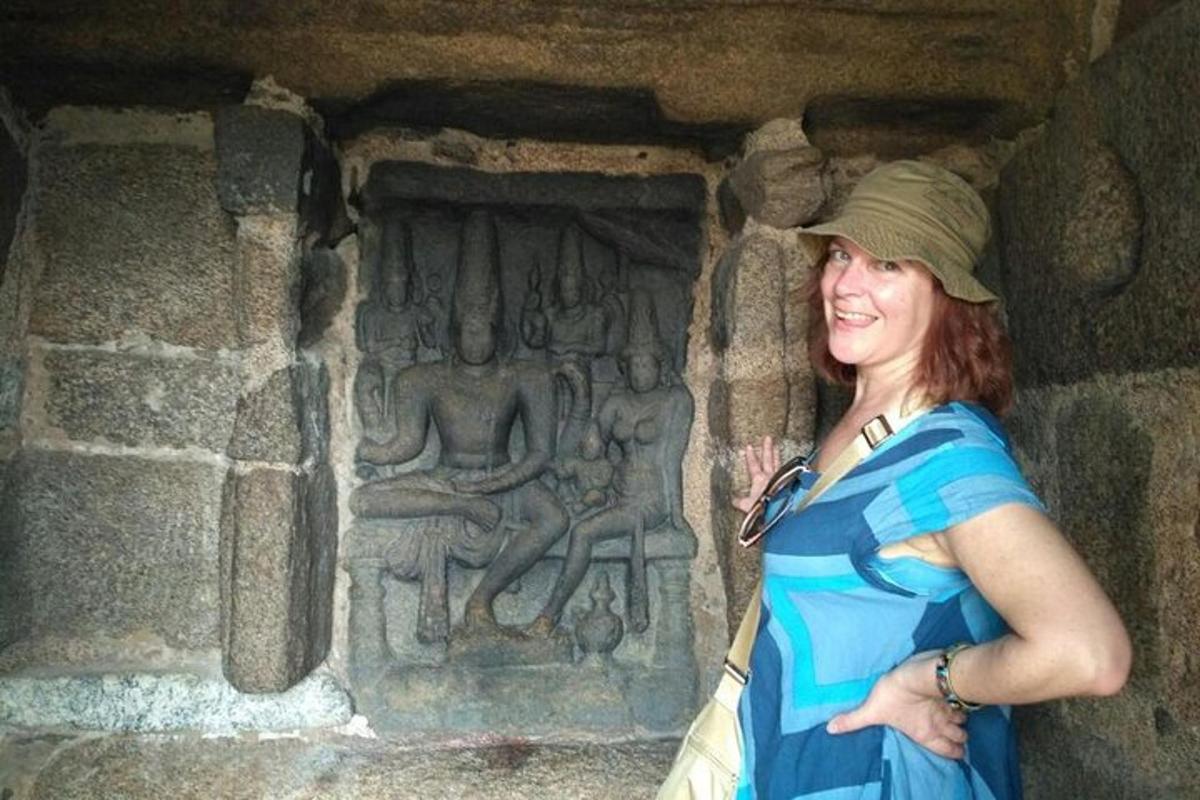 a woman standing in front of a wall with a carving