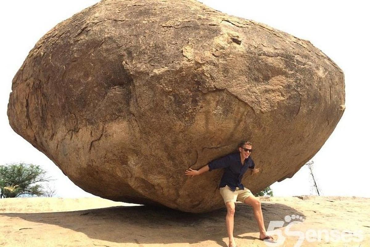 a man standing in front of a large rock