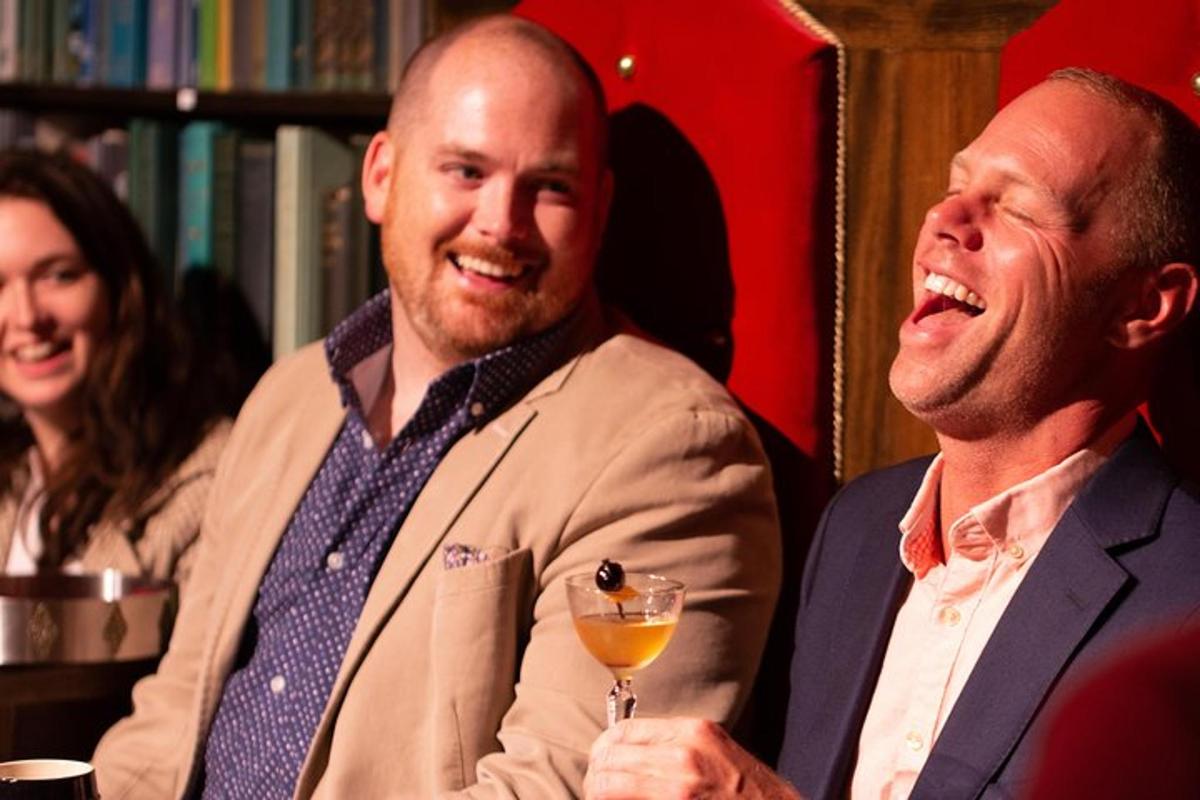 two men laughing while holding a glass of wine