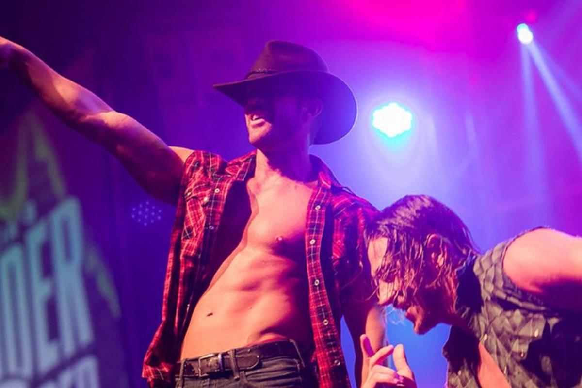 en skjorteløs mand iført en cowboyhat på en scene