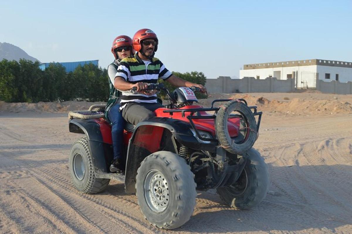 two people riding on a four wheeler in the desert