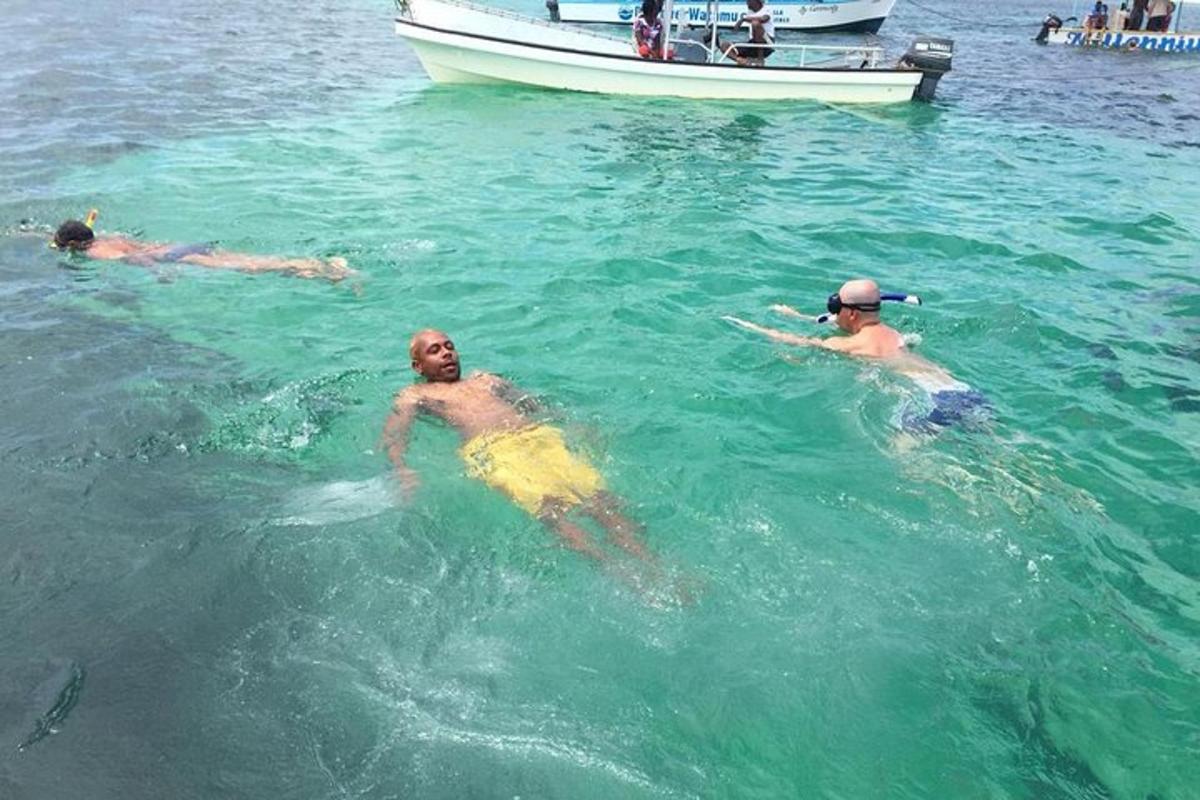 three men swimming in the water with a boat