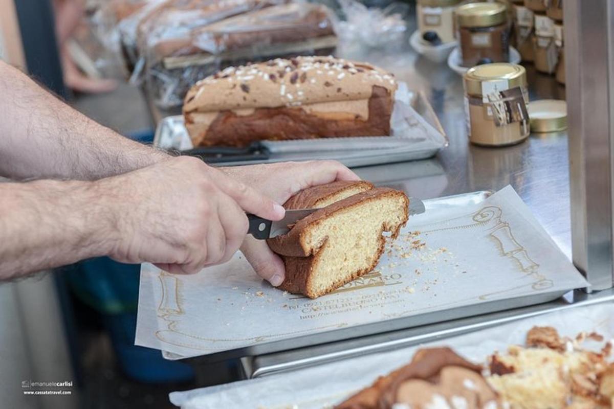 a person cutting a piece of bread with a knife
