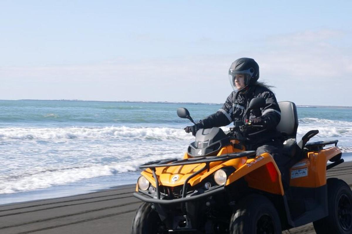 una persona conduint un quad a la platja