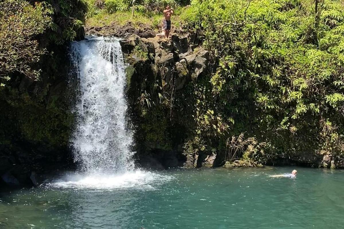 seseorang berenang di kolam di hadapan air terjun