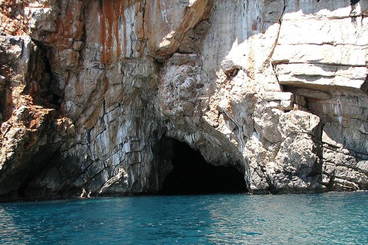 una grotta sul fianco di una scogliera con acqua blu