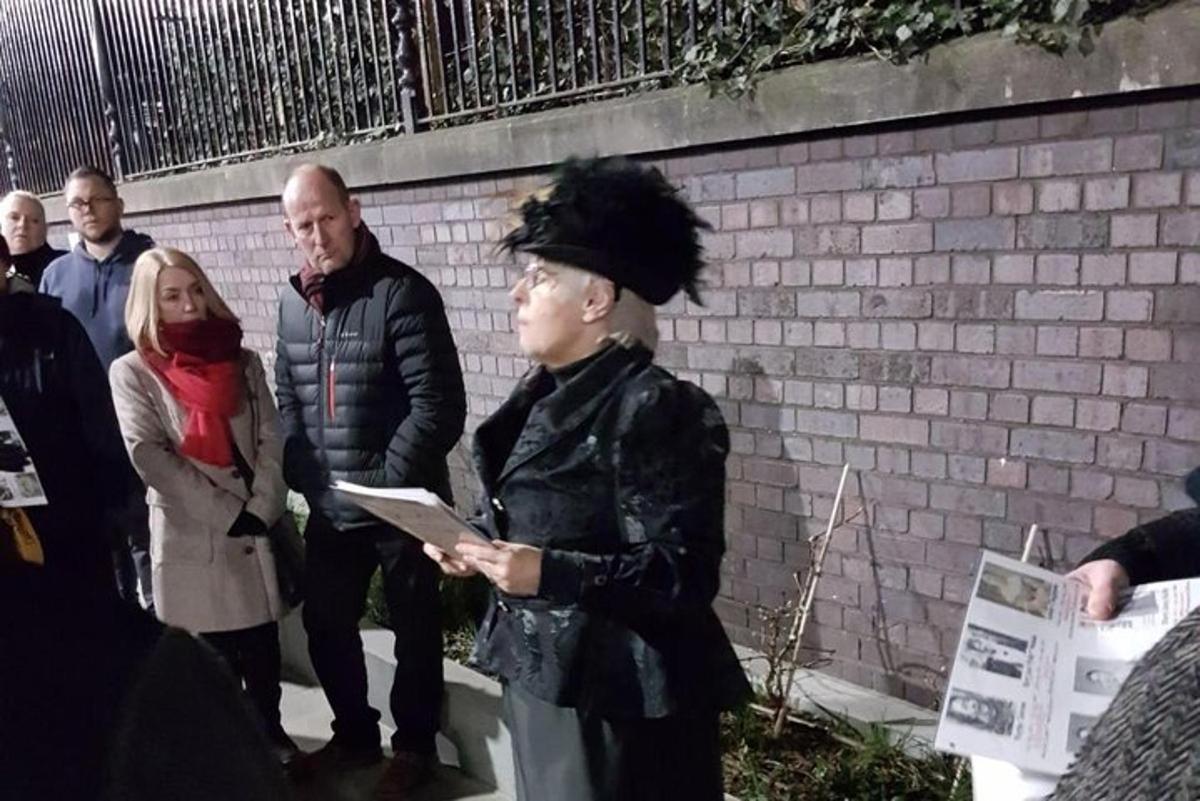 skupina lidí stojící vedle cihlové zdi