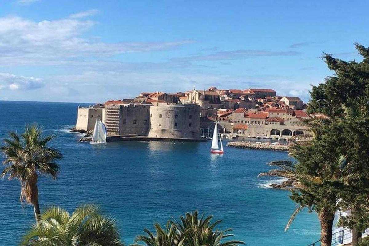 um pequeno barco à vela na água em frente a um castelo