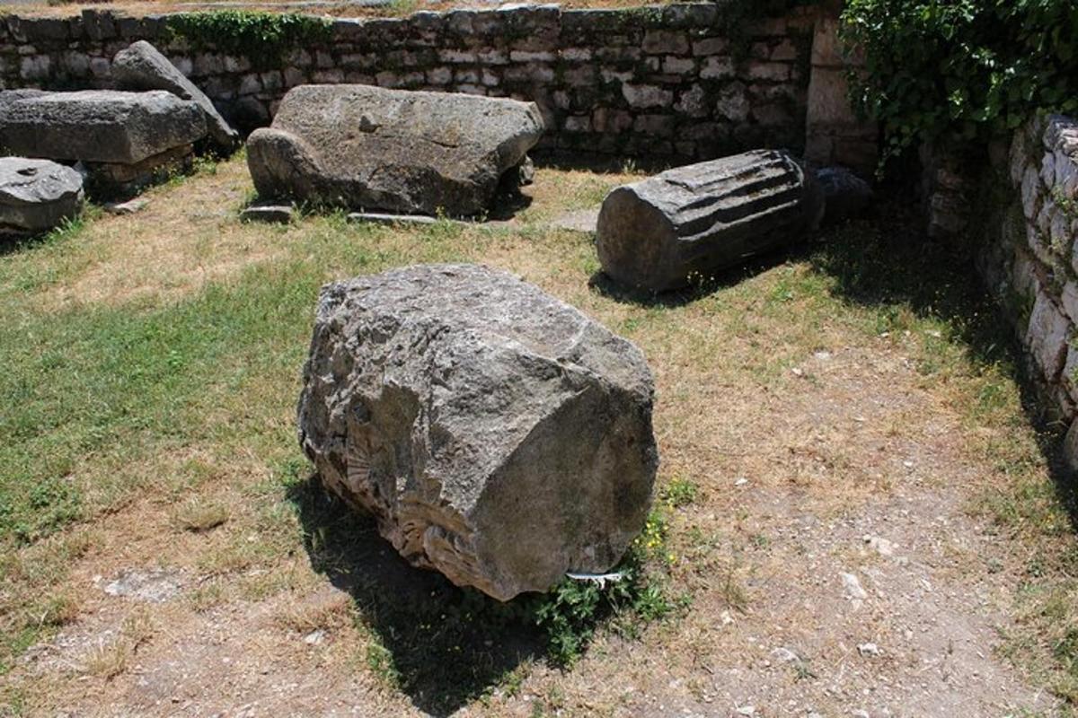 a large rock sitting on the grass next to a wall