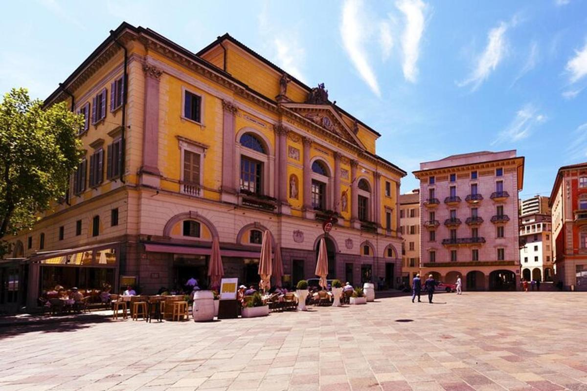 a group of buildings with tables and chairs in a courtyard