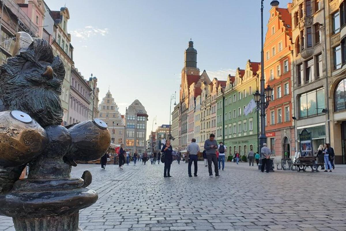 egy városi utca, egy oszlopra állított macskát ábrázoló szoborral