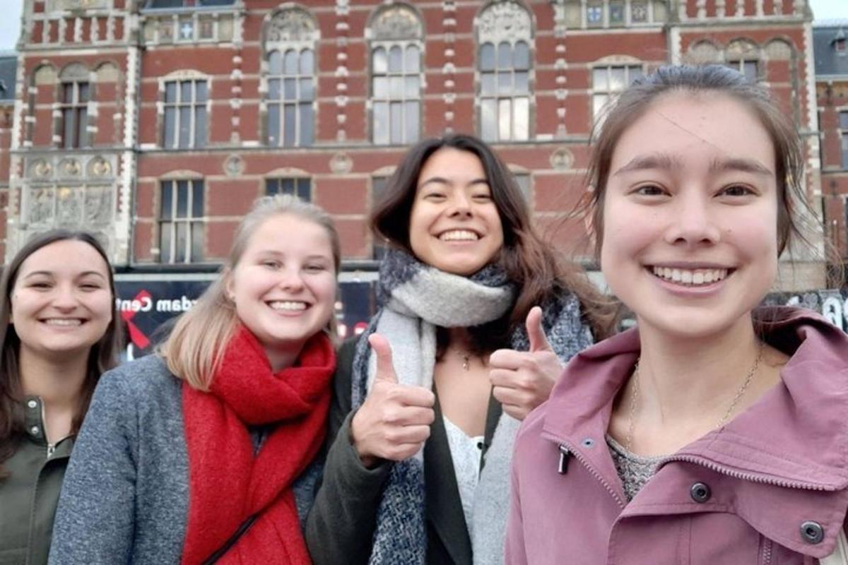 un gruppo di donne che fanno il gesto del pollice in su davanti a un edificio