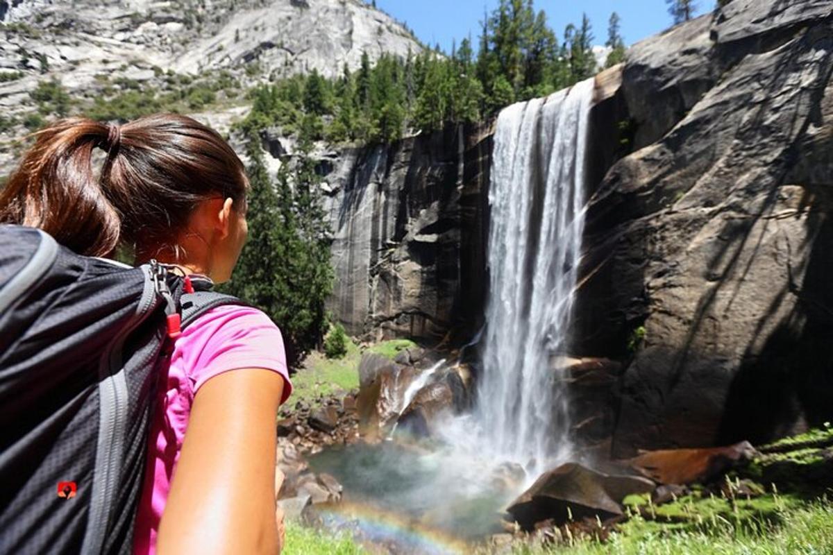 a girl with a backpack looking at a waterfall