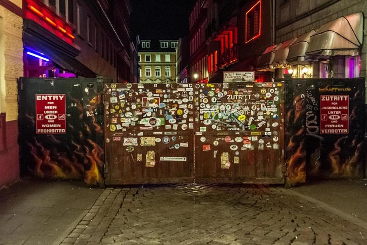 a fence covered in stickers on a street at night