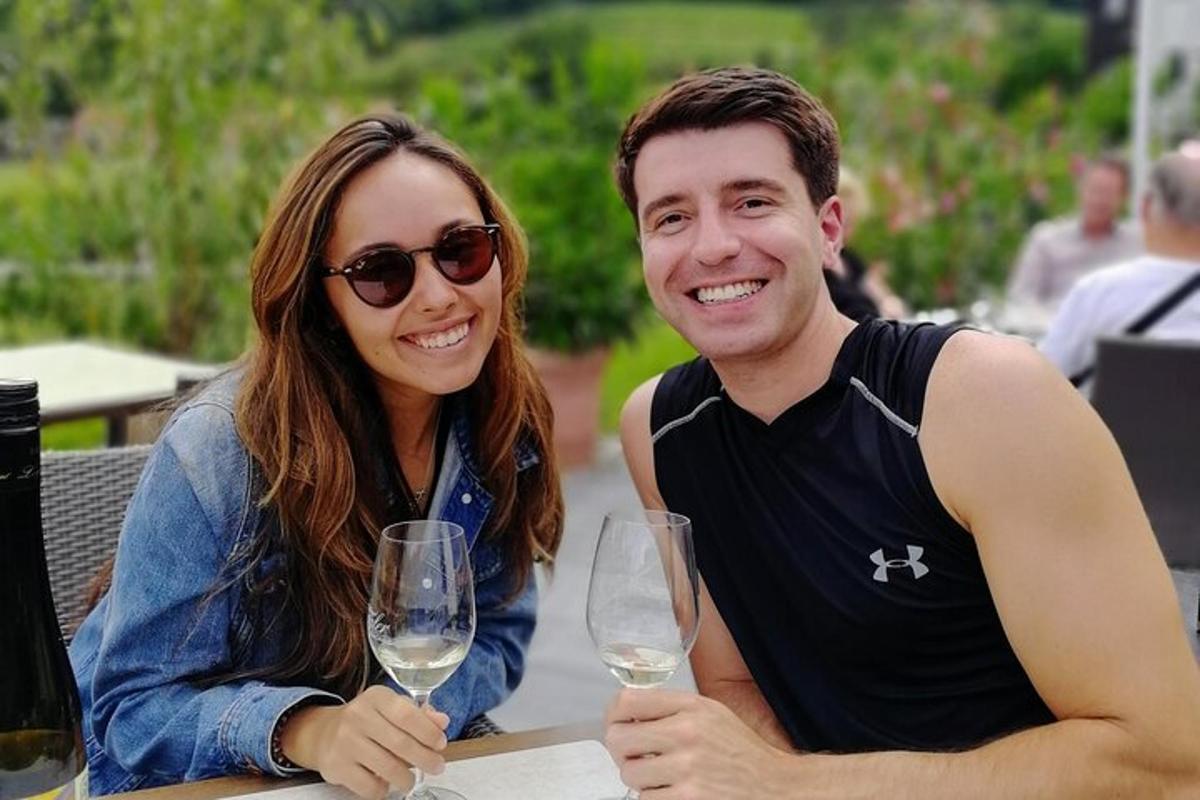 un bărbat și o femeie așezați la o masă cu pahare de vin